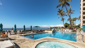 Ein Poolbereich mit Liegestühlen und Sonnenschirmen, einem Whirlpool und Blick auf den Ozean.