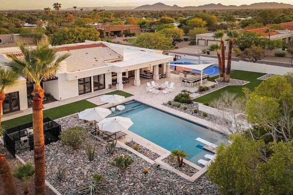 A modern house with a swimming pool, patio, and surrounding landscape. - SWSS 7BR Luxury Estate | Pool, Sport Court, Hot Tub, Games (Scottsdale)
