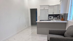 A modern kitchen with white cabinets, a built-in microwave, and a coffee maker.