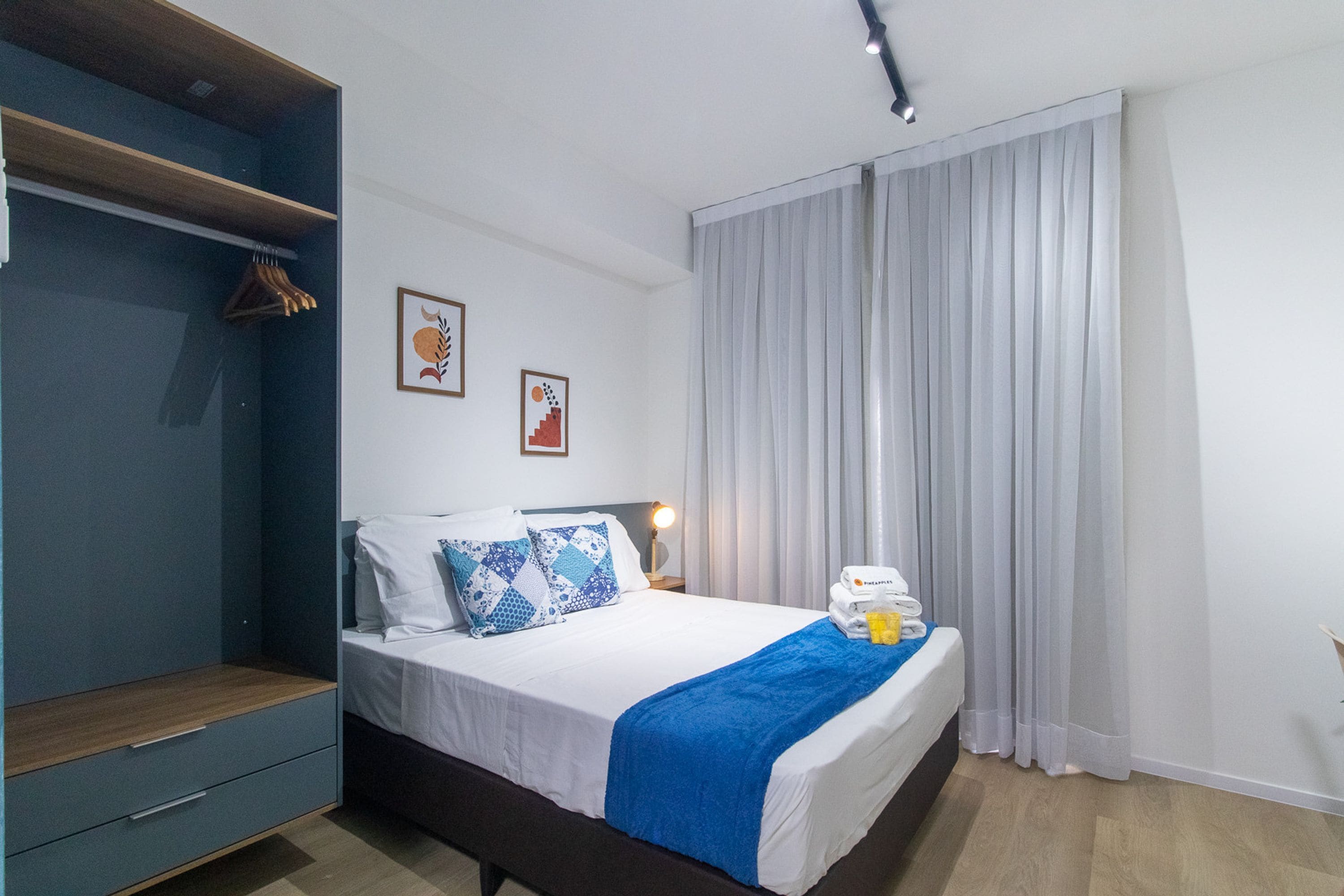 A hotel room with a bed, a bedside table, a wardrobe, and a window with curtains.