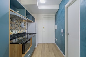 A compact kitchen with a microwave, stove, and tiled backsplash.