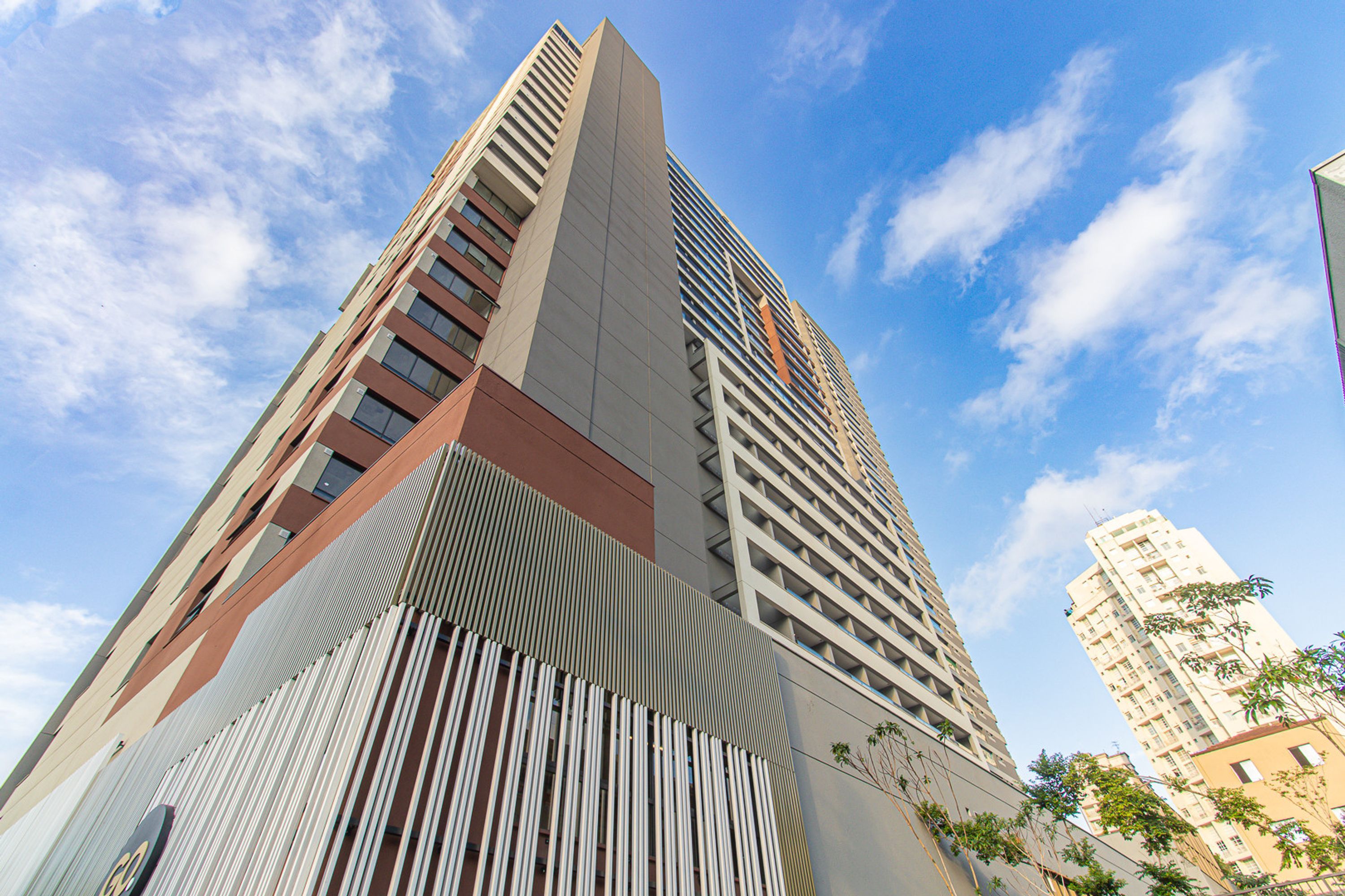 A high-rise building with a modern architectural design, featuring a prominent vertical element and a series of balconies.