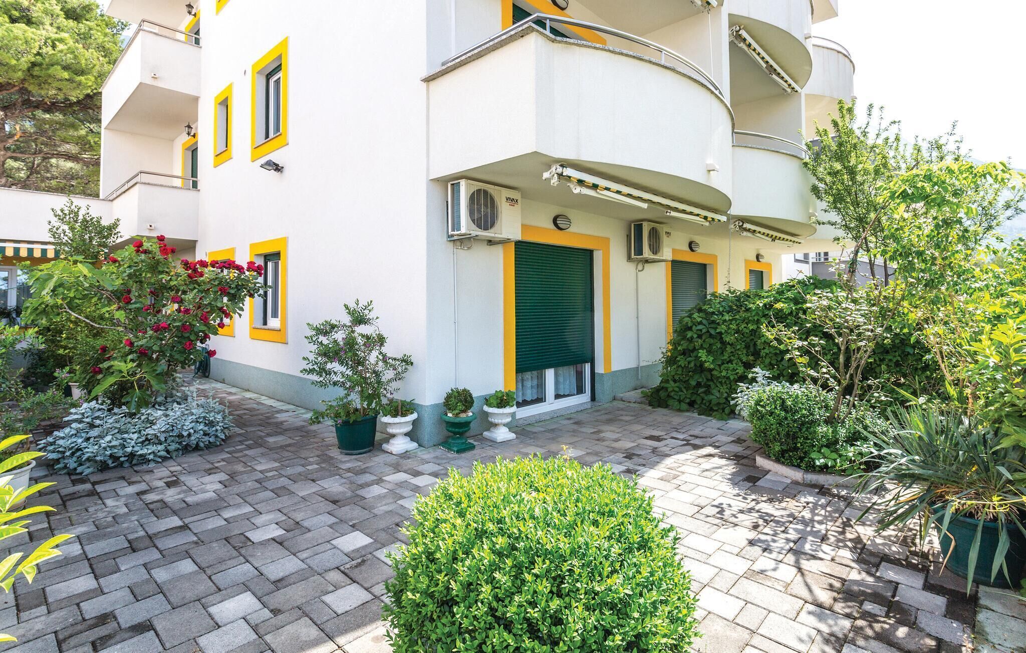 Un edificio moderno con un patio que incluye plantas en macetas y un sendero de ladrillo.