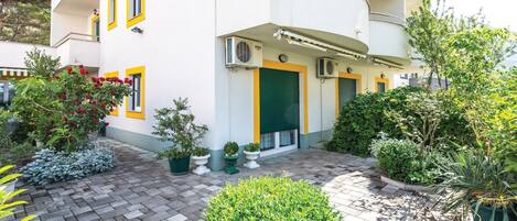 Un edificio moderno con un patio que incluye plantas en macetas y un sendero de ladrillo.
