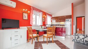 A compact kitchen with a dining area, a flat-screen TV, and a refrigerator.