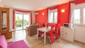 A room with a dining table, red chairs, a sofa, a cabinet, and a microwave. - Stunning apartment in Makarska with WiFi (Makarska)