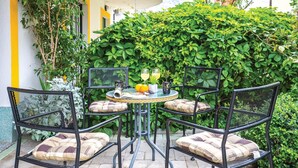 A small outdoor seating area with a round table and four chairs, surrounded by lush greenery and a yellow wall. - Stunning apartment in Makarska with WiFi (Makarska)