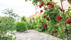 A garden with a paved walkway, various plants, and a building in the background. - Stunning apartment in Makarska with WiFi (Makarska)