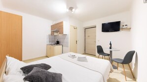 A hotel room with a bed, a small kitchenette, a TV, and a dining area with chairs. - 1 bedroom lovely apartment in Split (Split)