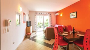 Una habitación de hotel con cama, televisión, mesa de comedor con sillas, teléfono y vista al exterior por una puerta corrediza.