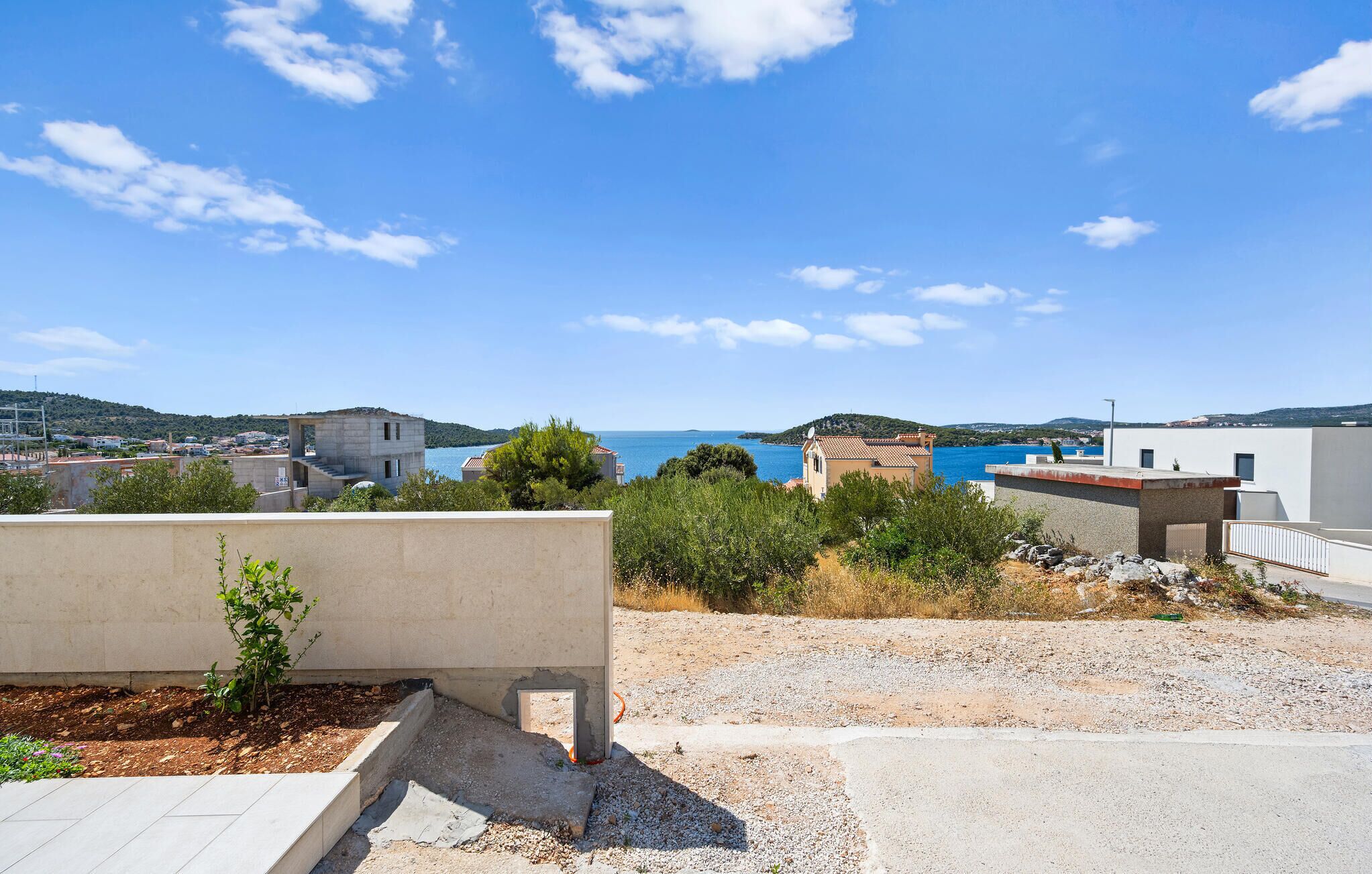 Ein Küstenwohngebiet mit Häusern, blauem Himmel und Blick aufs Meer.