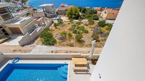 Un espace piscine moderne offrant une vue dégagée sur la mer et les bâtiments environnants.