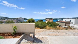 A coastal residential area with houses, a clear blue sky, and a view of the sea.