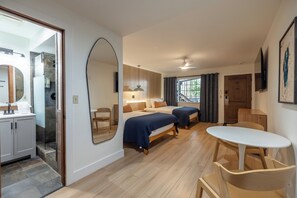 A hotel room with a bed, bedside table, mirror, and a view of the outside. - The Iceberg Tahoe (South Lake Tahoe)