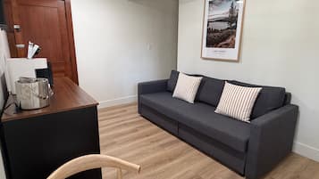 A living area with a dark grey sofa, two striped pillows, a wooden coffee table, and a framed picture of a landscape on the wall.