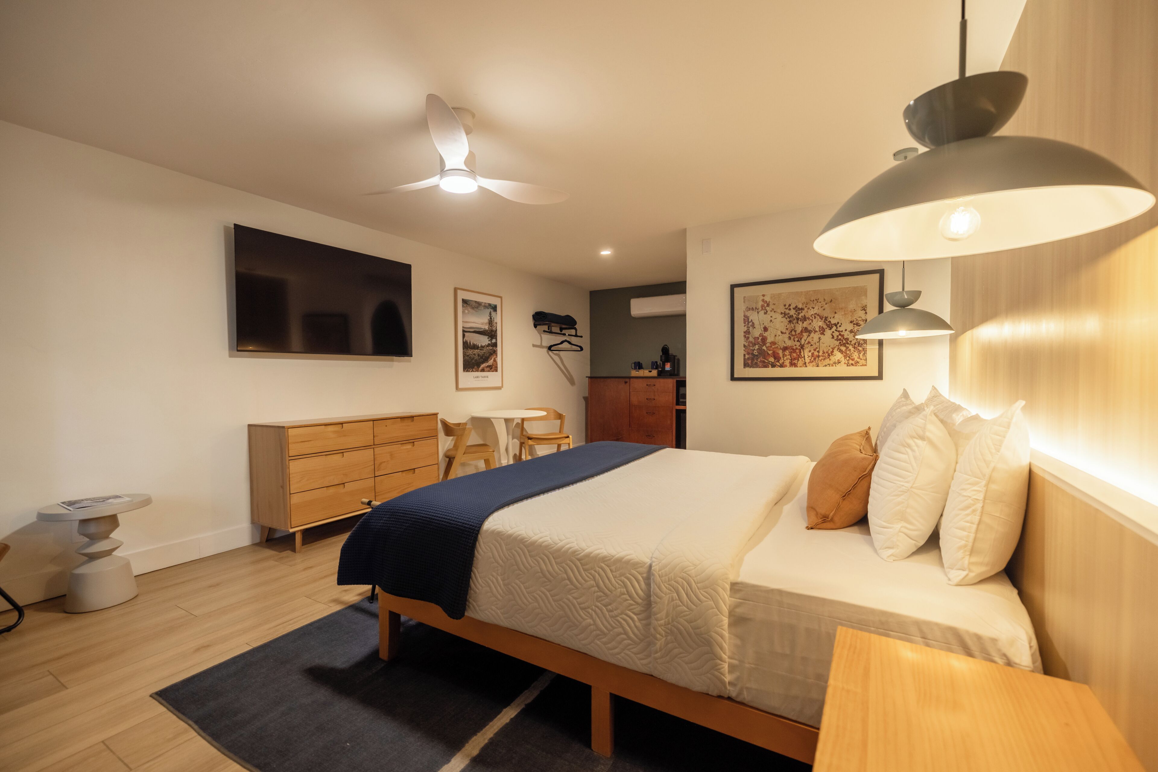 Un dormitorio con cama, mesita de noche, lámpara, cómoda y televisor.
