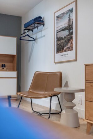 A modern room with a brown leather chair, a small round table, and a framed picture of Lake Tahoe on the wall.