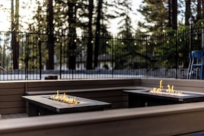 An outdoor seating area with two square tables, each with a built-in fire feature.