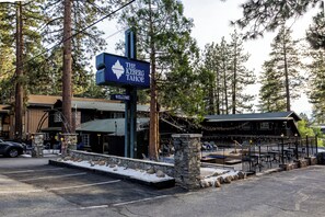 A sign for The Iceberg Tahoe, a building with a stone facade, and a parking area with snow.