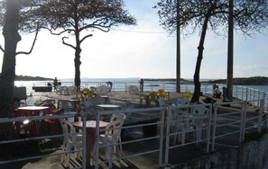 A seaside patio with tables and chairs, overlooking the sea. - 4°D3 Your Beach Retreat on the Coast Awaits You > 1-minute-from-the-sea (Itapuã Vila Velha)