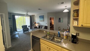 A compact kitchen with a dishwasher, double sink, and a coffee maker.