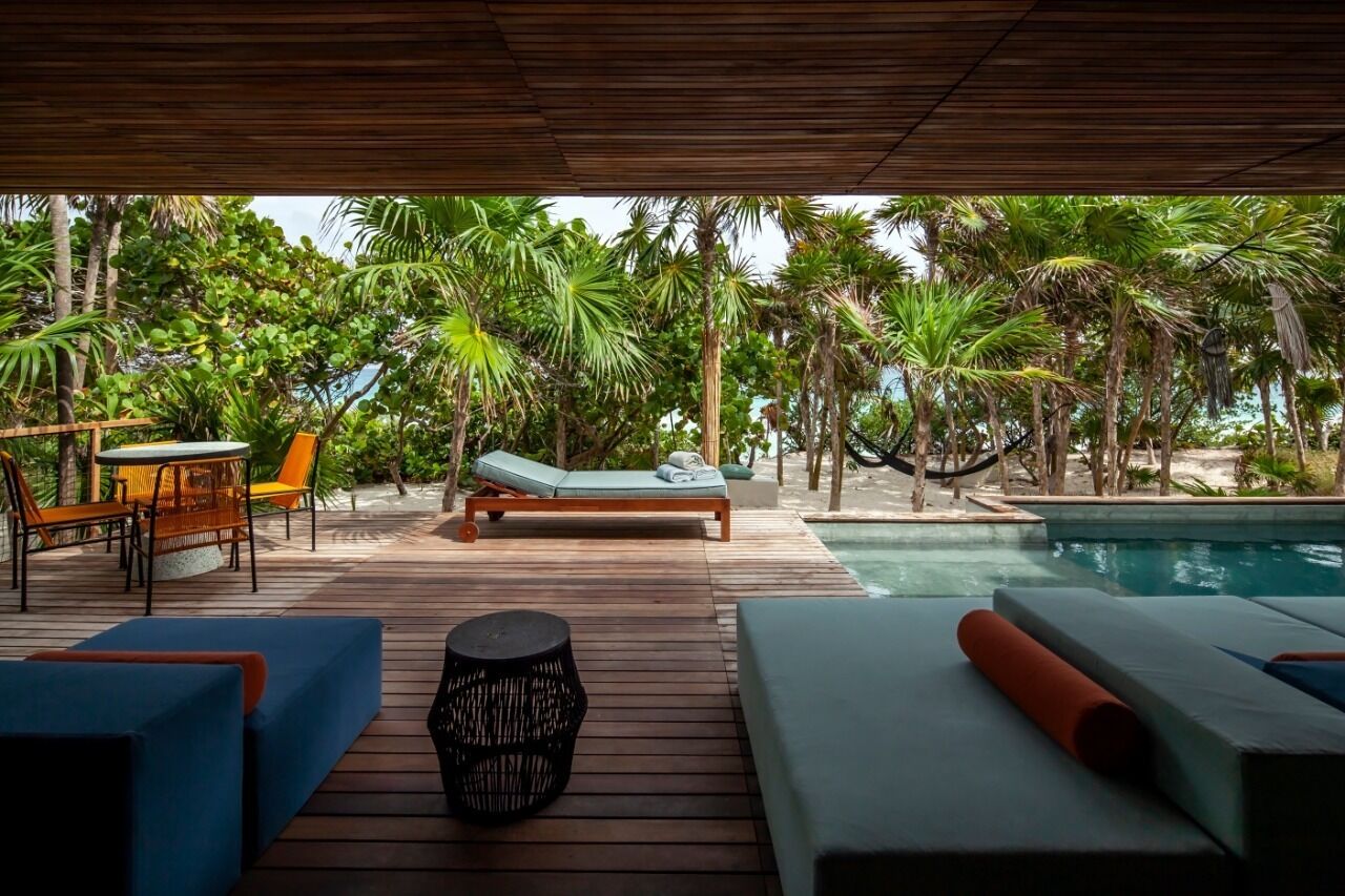 A wooden deck with lounge chairs, a small table, and a pool.