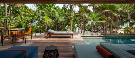 A wooden deck with lounge chairs, a small table, and a pool.