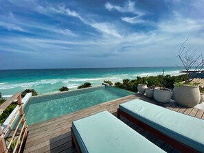 Eine Holzterrasse mit Pool mit Blick auf den Ozean.