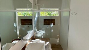 Un baño moderno con un espejo grande, un lavamanos blanco y un mueble de tocador de madera.