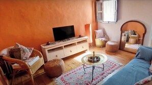 En hyggelig stue med en sofa, fjernsyn, et lille bord og en stol.