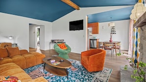 A modern living room with a blue ceiling, orange furniture, and a patterned rug. - Groovy Getaway - Retro Vibes and Modern Comfort (Tulsa)
