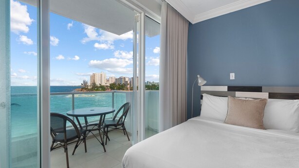 A hotel room with a balcony, a bed, and a view of the ocean. - Waterside Historic District Sweeping Views (San Juan)