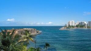 A coastal view with a historic fort, palm trees, and modern buildings along the shoreline. - Waterside Historic District Sweeping Views (San Juan)