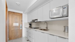 A modern kitchen with white cabinets, a stainless steel sink, a microwave, and a coffee maker. - Waterside Historic District Sweeping Views (San Juan)