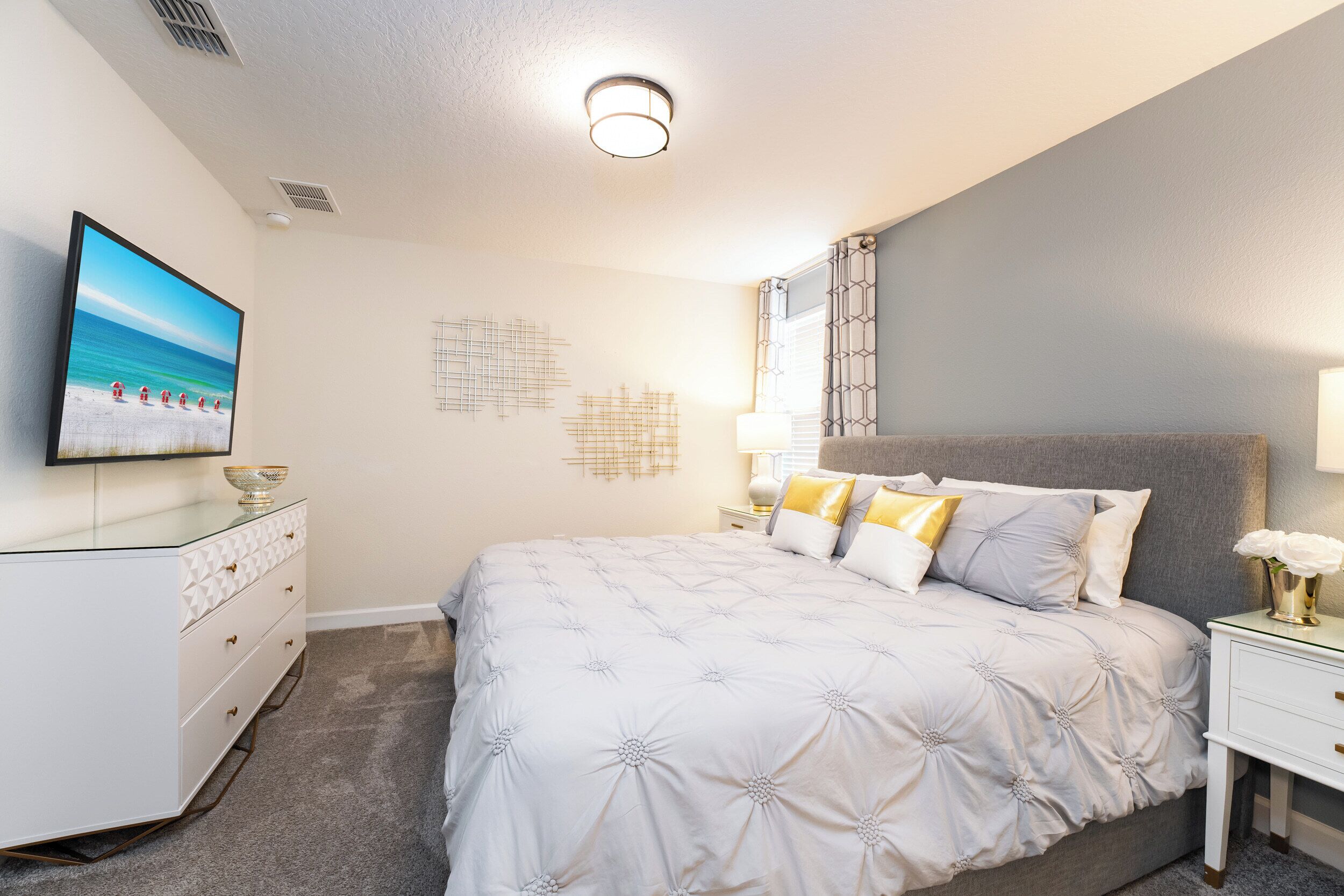 A bedroom with a large bed, a television on the left, and a nightstand with a lamp.