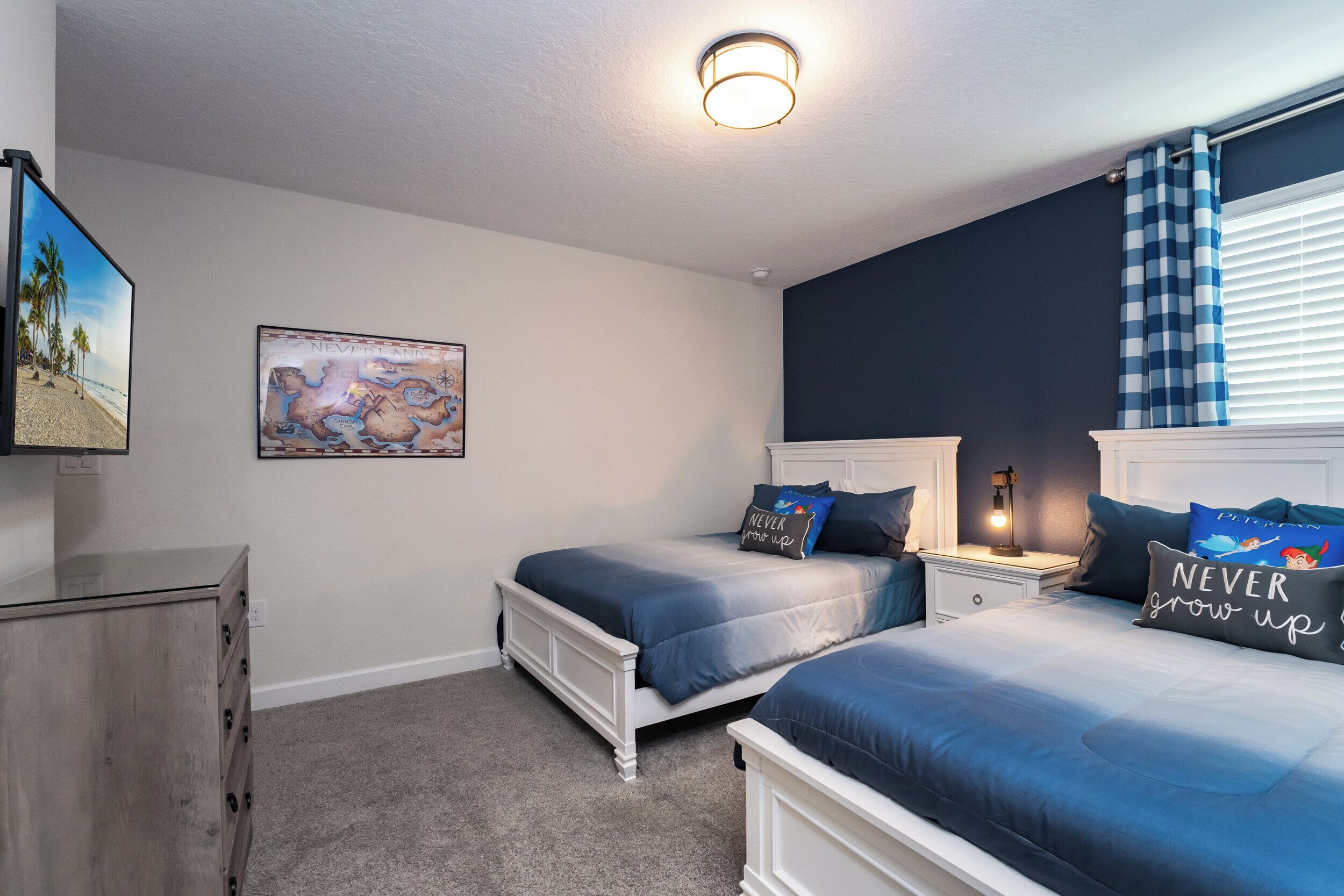 A bedroom with two beds, a dresser, a map on the wall, and a window with blinds.
