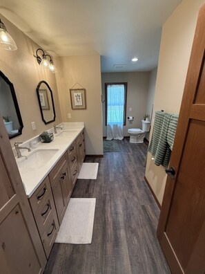 A bathroom with a double sink, vanity, and a shower area.