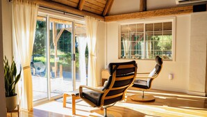 A room with two modern chairs, a wooden ceiling, and large windows.