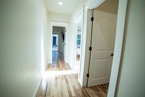 Un couloir au plancher en bois menant à une porte fermée.