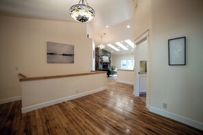 A spacious hallway with wooden flooring, a staircase, and a chandelier. - Sleeps 24 • Forest • Sauna • Massage Chair (Eugene)