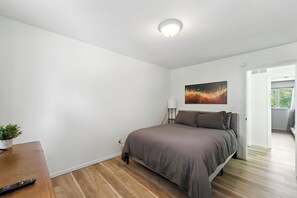 Ein Schlafzimmer mit einem Bett, einem Nachttisch, einer Lampe und einem Bild an der Wand.