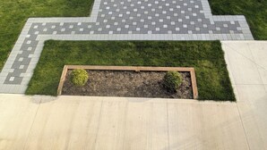 A paved area with a geometric pattern, a grassy border, and a raised planter box with plants. - Fully Furnished Holiday Rental 02 BR Suite (Surrey)