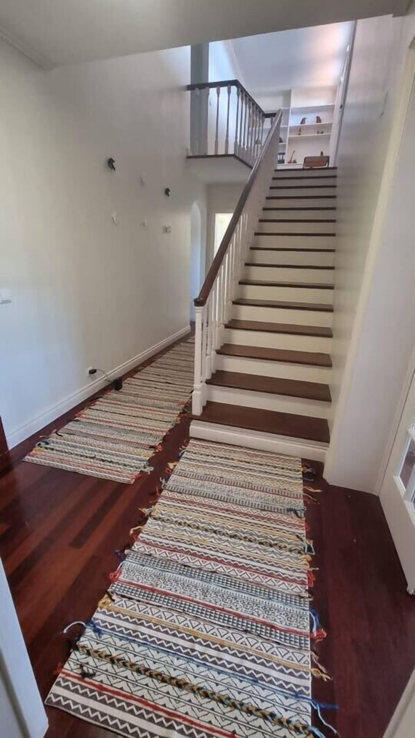 A staircase with a wooden handrail and a patterned rug on the floor.