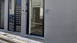 Una entrada moderna de edificio con puerta de vidrio, cerradura con teclado y un letrero que dice 'AL'.
