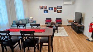 Uma sala de estar com área de jantar, sofás, televisão e extintor de incêndio.