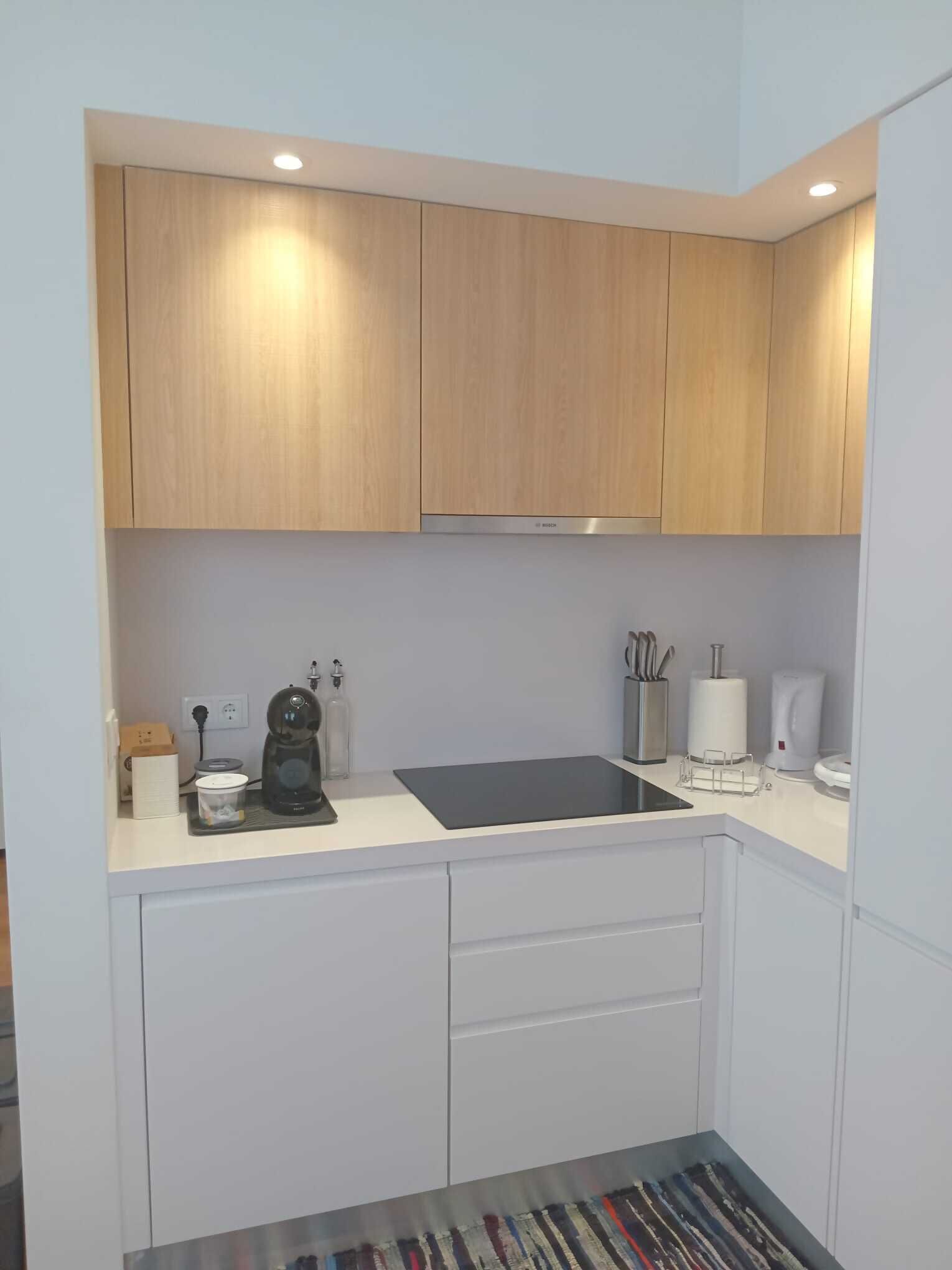 A compact kitchen with wooden cabinets, a black countertop, and white drawers.