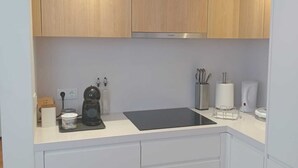A compact kitchen with wooden cabinets, a black countertop, and white drawers. - Sky Dream Apartment (Ponta Delgada)