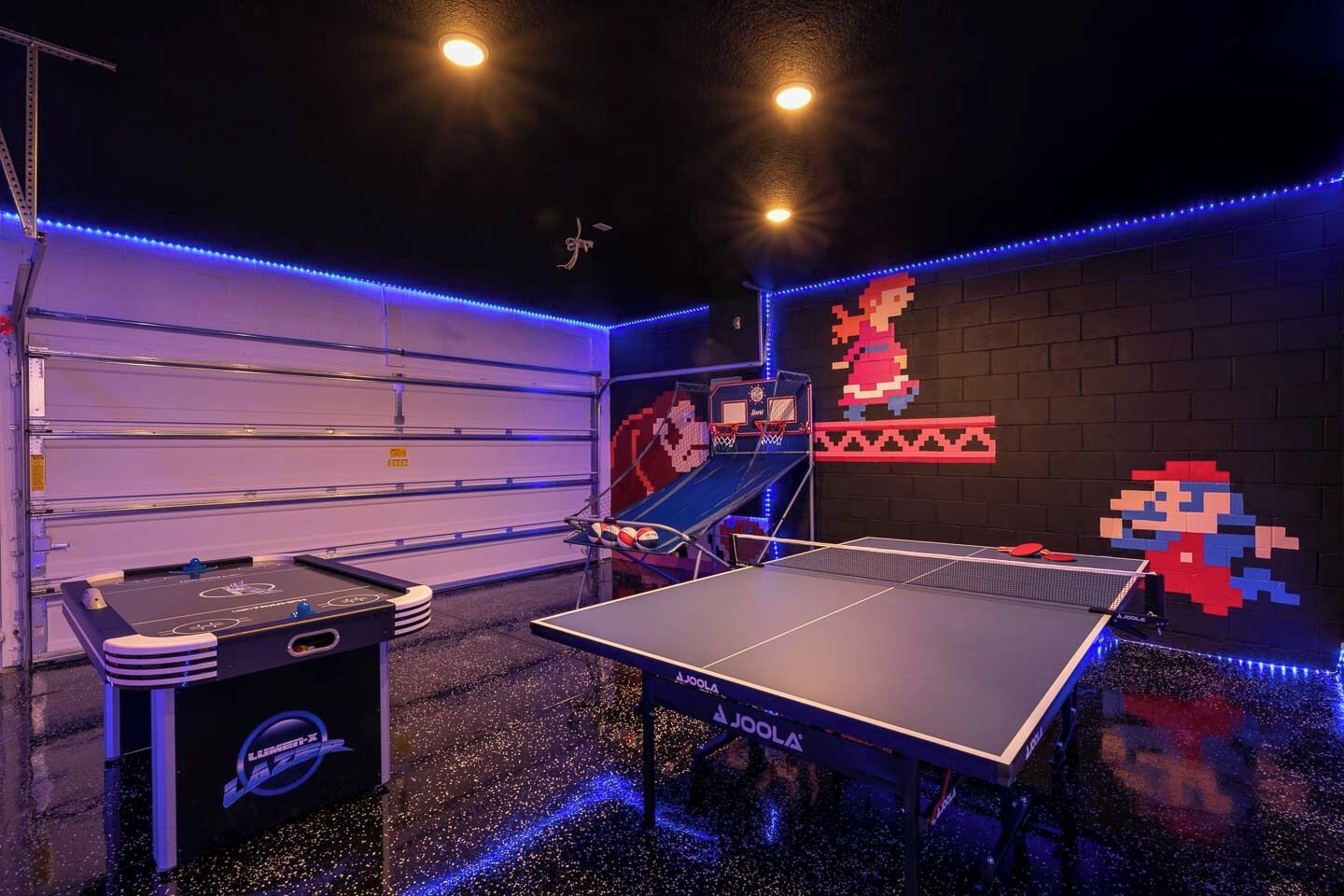 Et spillerum med pingpongbord, et fodboldbord og en væg dekoreret med pixelkunst.