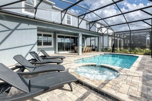 Una piscina exterior techada con sillones de descanso, un jacuzzi y un patio amoblado.