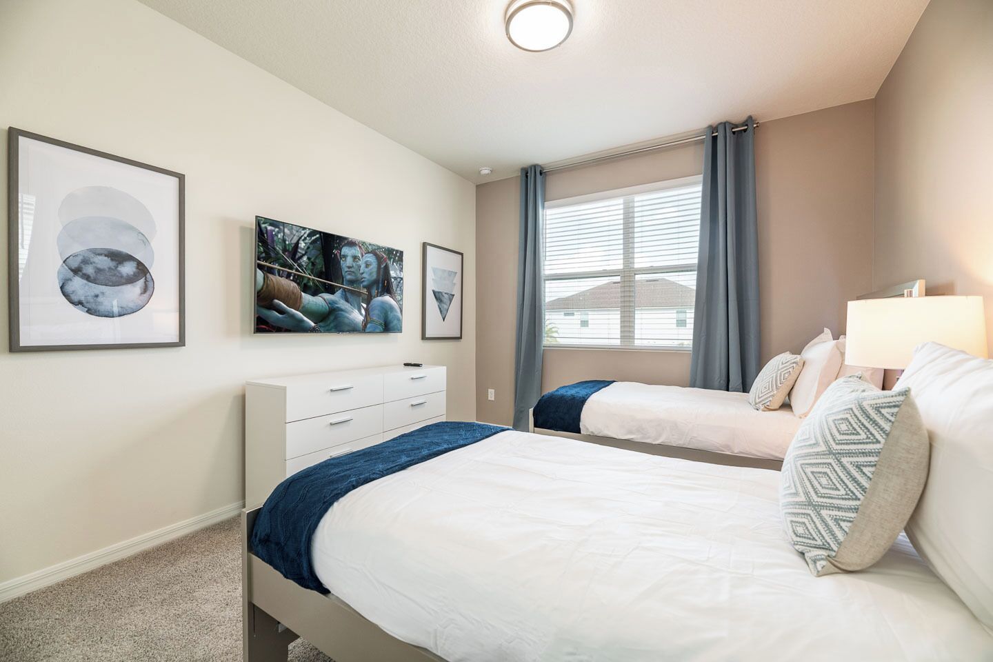 A bedroom with two beds, a dresser, and artwork on the wall.